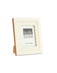 The 705140 5x7 Floral Resin Frame by BIDK Home features scalloped edges, an elegant white design, and stands on a wooden easel back. Fits a 5"x7" photo—ideal for displaying cherished memories and enhancing your home decor.
