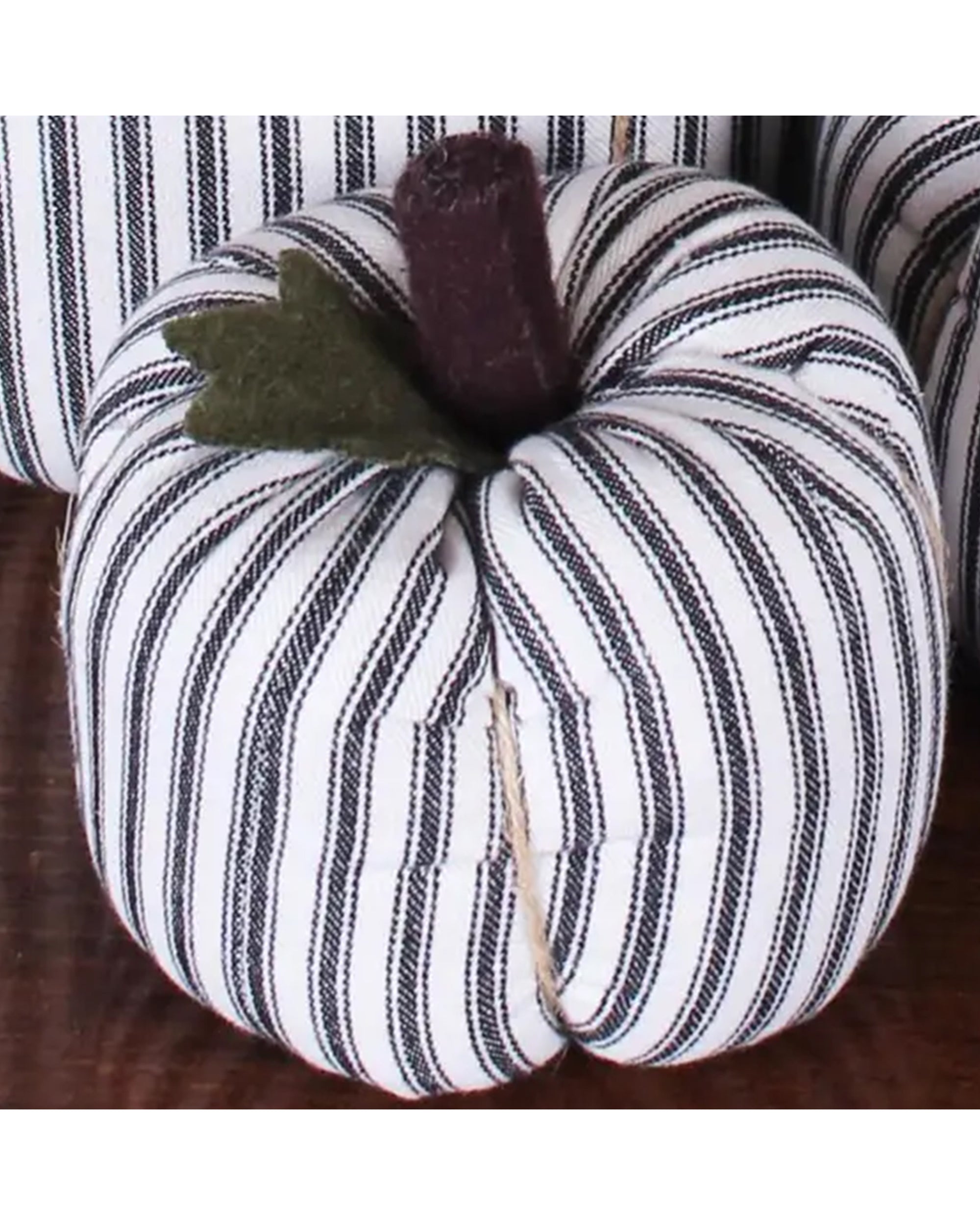 The Faire Pumpkin features black and white vertical stripes, a brown stem, and a green felt leaf, making it a charming autumn ornament for farmhouse decor.