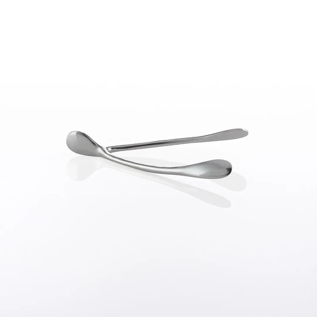 The Wishbone /Small, a pair of sleek, handcrafted aluminum tongs with rounded ends, rests on a glossy white surface, casting a subtle reflection.