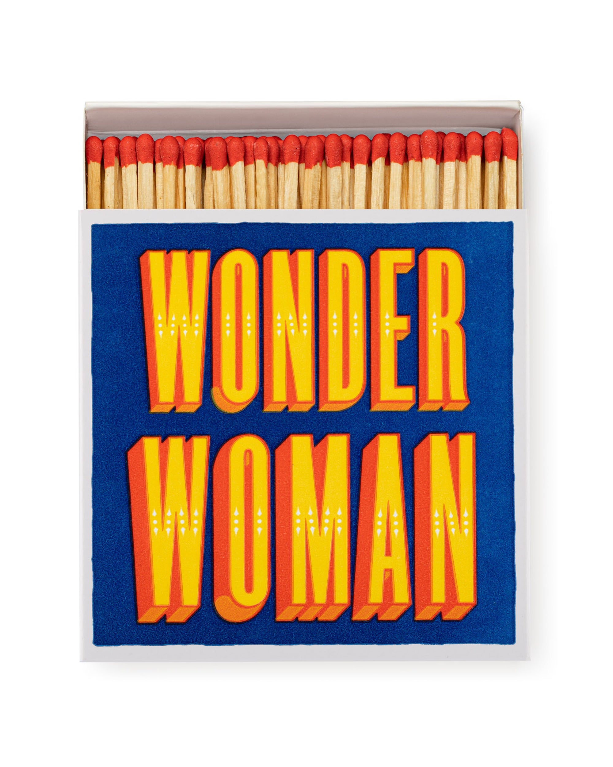 A box of AG Safety Matches by Faire, featuring red-tipped decorative matchsticks. The blue matchbox displays bold yellow and orange text reading "WONDER WOMAN." Great for collectors or as a unique gift.