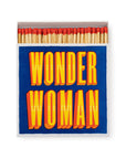 A box of AG Safety Matches by Faire, featuring red-tipped decorative matchsticks. The blue matchbox displays bold yellow and orange text reading "WONDER WOMAN." Great for collectors or as a unique gift.
