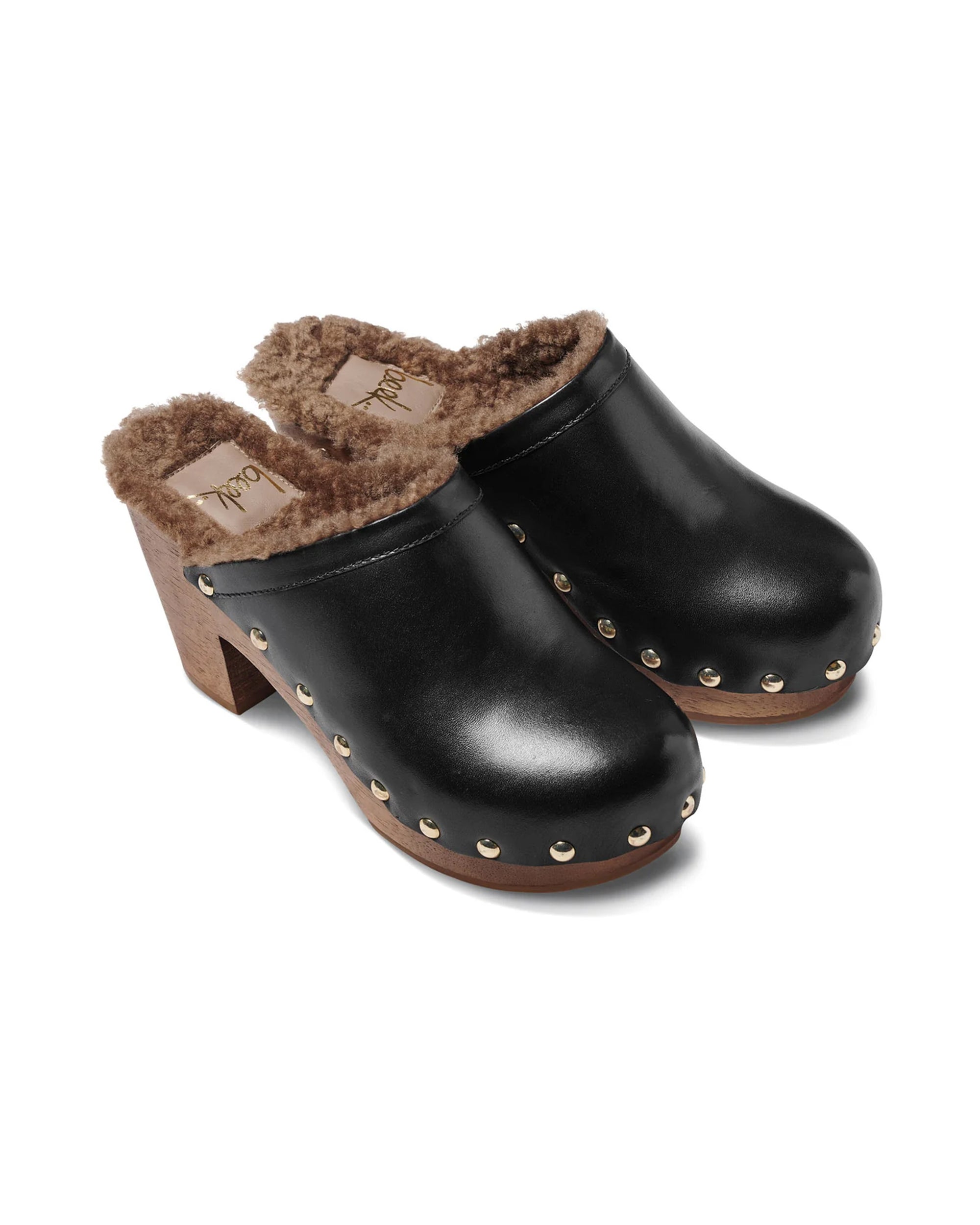 The Beek WOODPECKER clog features black leather, brown wooden heels, faux fur lining, and metal studs along the base.