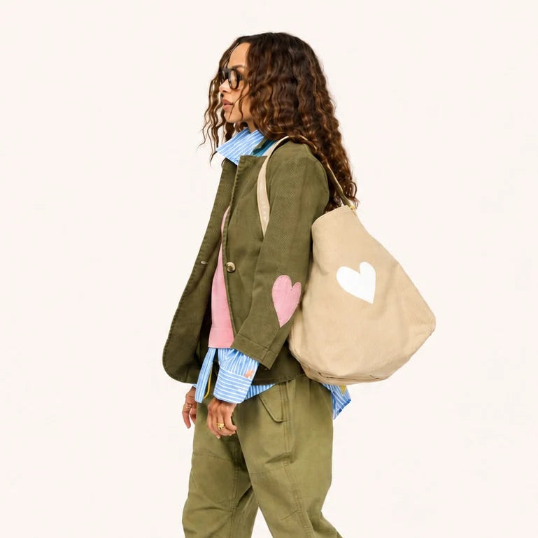 Green Kerri Rosenthal blazer with pink heart, styled with a beige tote for a fresh, modern look.
