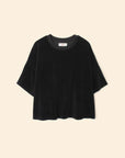The Roe Top by Xirena is a loose-fitting black short-sleeve t-shirt made from a soft cotton blend with a round neckline, shown on a beige background.