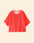 The Roe Top by Xirena is a loose-fitting, short-sleeved T-shirt in bright coral pink, made from a soft cotton blend with a crew neckline, shown against a light beige background.
