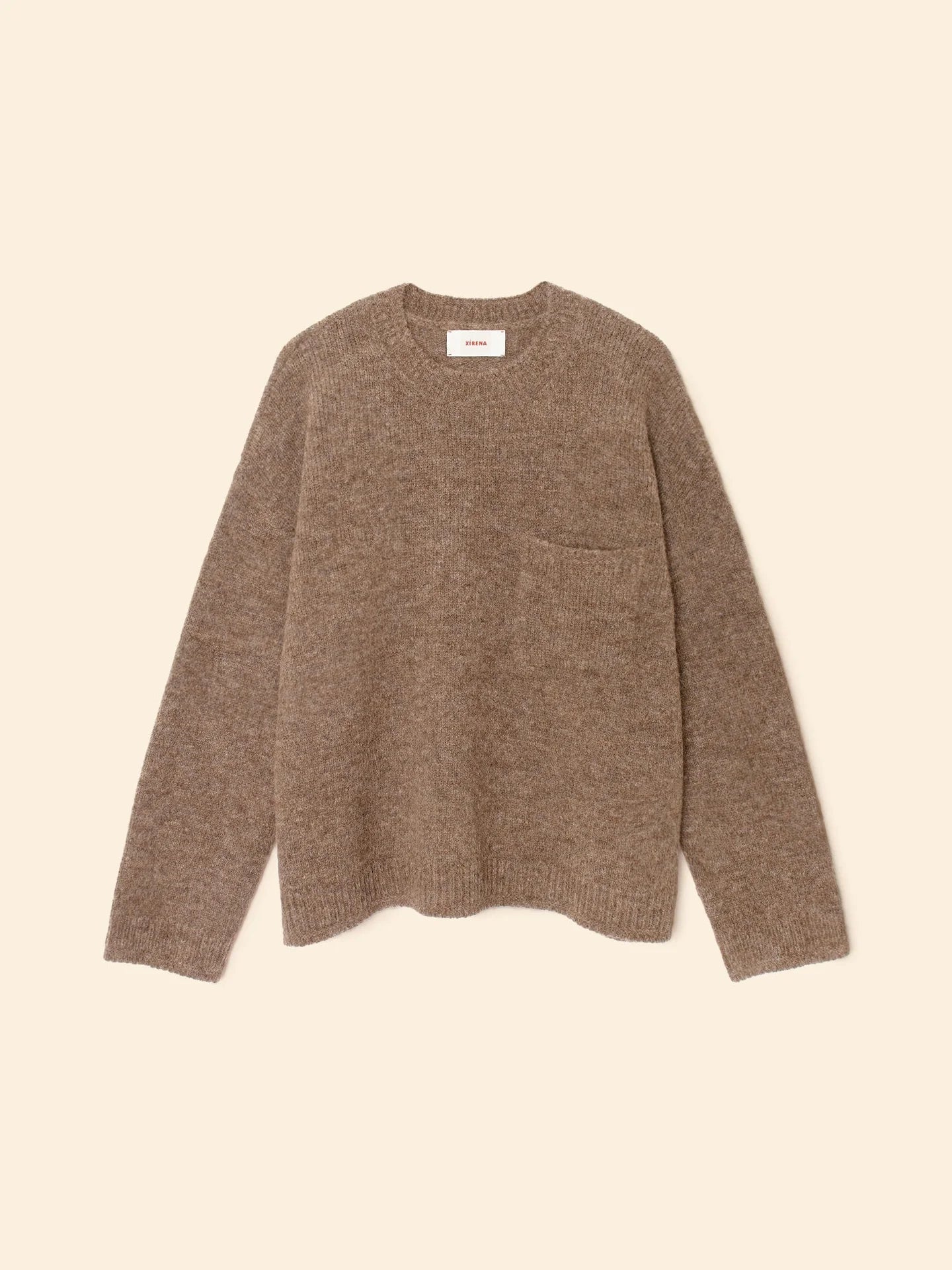 The Julien Sweater by Xirena is a brown, long-sleeve crew neck pullover featuring a subtle chest pocket, displayed flat on a cream-colored background.