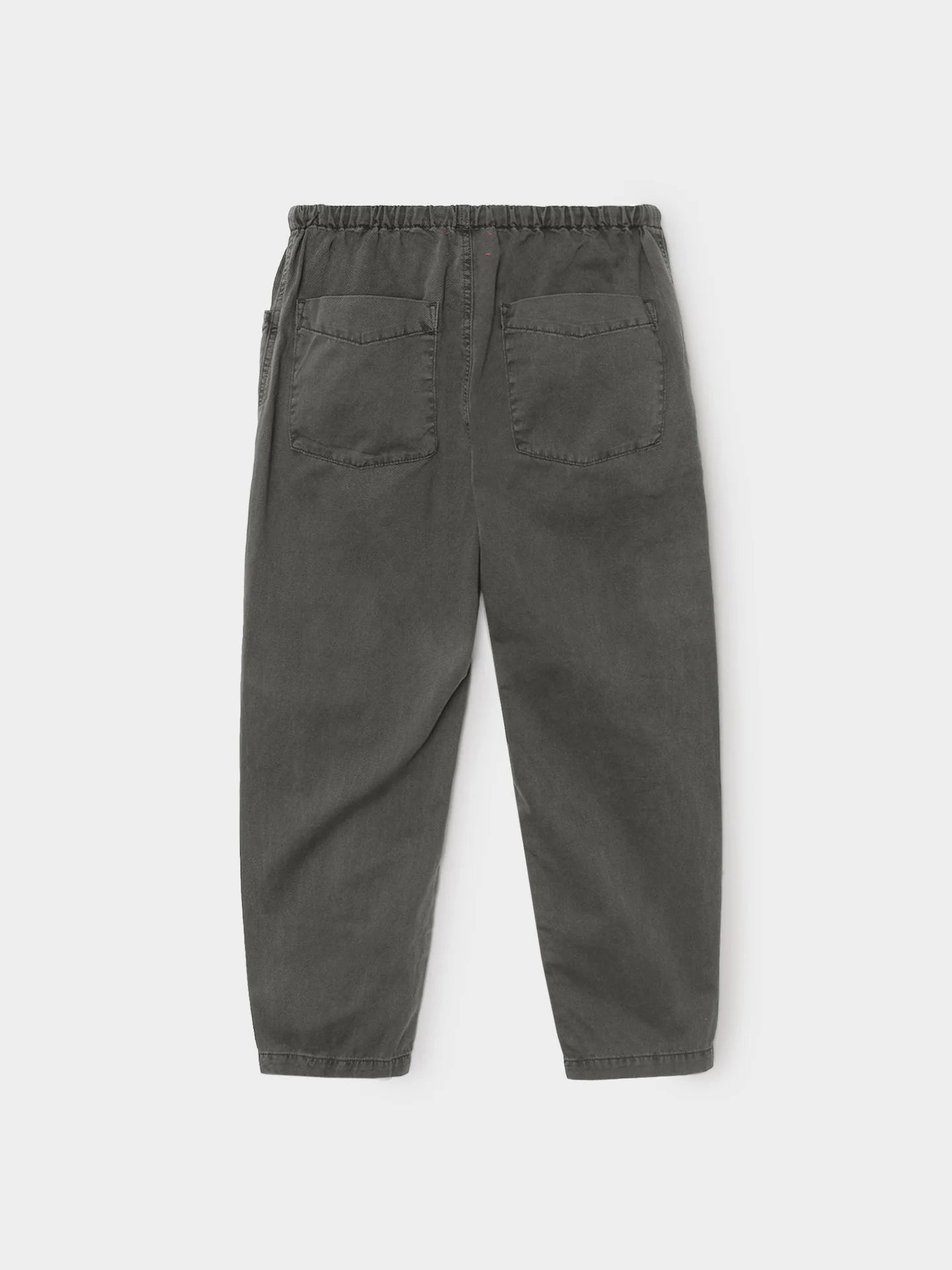 The Xirena Baxter Pant is a loose-fitting, dark gray cotton twill pull-on style with an elastic waistband and two large back pockets, shown flat on a plain white background.