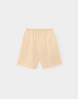 The Rocco Short by Xirena is a beige, knee-length French terry sweatshort with an elastic waistband. Displayed flat on a light gray background, these vintage-washed shorts have a minimal design and no visible pockets or embellishments.