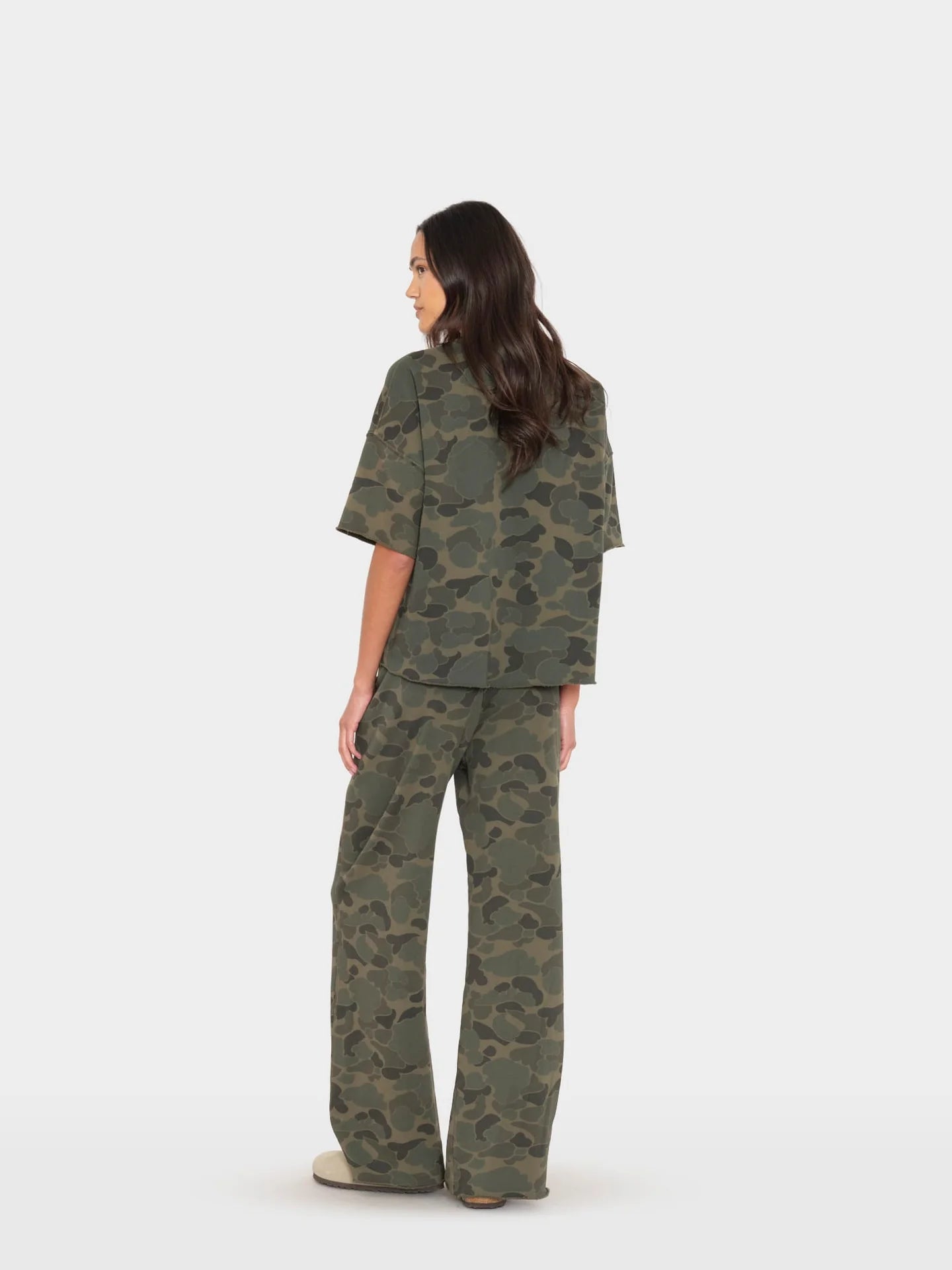 Xirena Renzo Sweatpant and matching top in neutral tones, shown from the back with beige shoes on a white background.