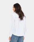 Xirena Amanda Shirt in white on woman with long brown hair, paired with blue jeans, back view.