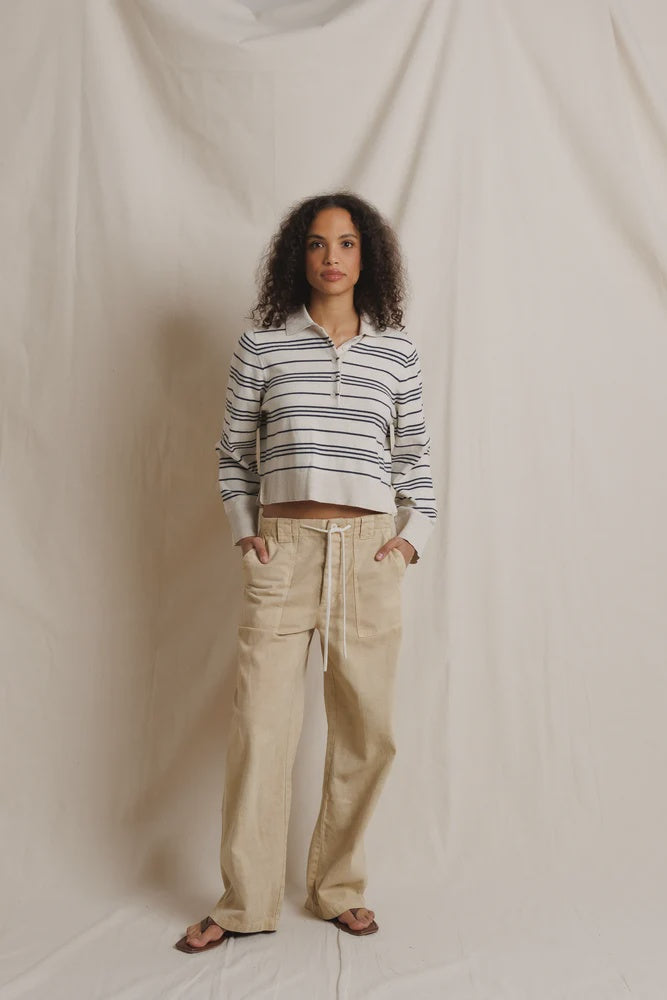 Perfectwhitetee Ximena striped sweater in cream, styled with beige pants and sandals by a soft fabric backdrop.