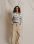 Perfectwhitetee Ximena striped sweater in cream, styled with beige pants and sandals by a soft fabric backdrop.