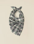 The Xirena Bandana, a versatile piece in green, gray, and white crinkled double plaid, is fashioned into a neat knot at the top and displayed on a plain, light background.