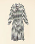 The Alanis Dress by Xirena is a midi shirtdress with a green, white, and black checkered pattern. It features long sleeves, a button-front design, and a waist tie, all displayed on a light background.