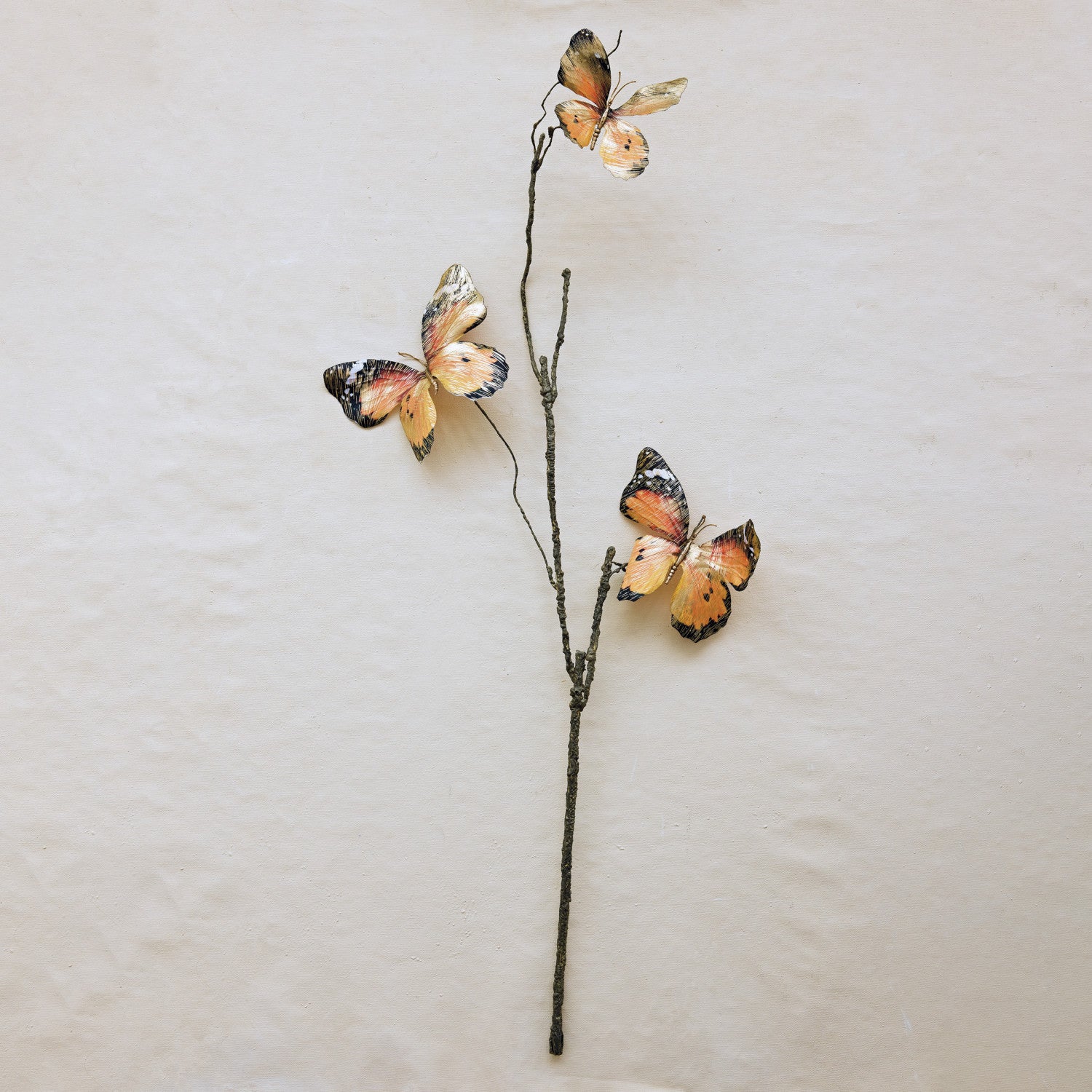 Three orange and black butterflies on a thin stem, Creative Co-op XT1539 Butterfly Stem, beige background.