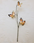 Three orange and black butterflies on a thin stem, Creative Co-op XT1539 Butterfly Stem, beige background.