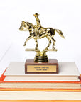 A golden figurine of a cowboy on a horse, mounted on a wooden base with a plaque reading "You're the Yee to my Haw," atop a stack of three colorful Arizona-style books by Faire.