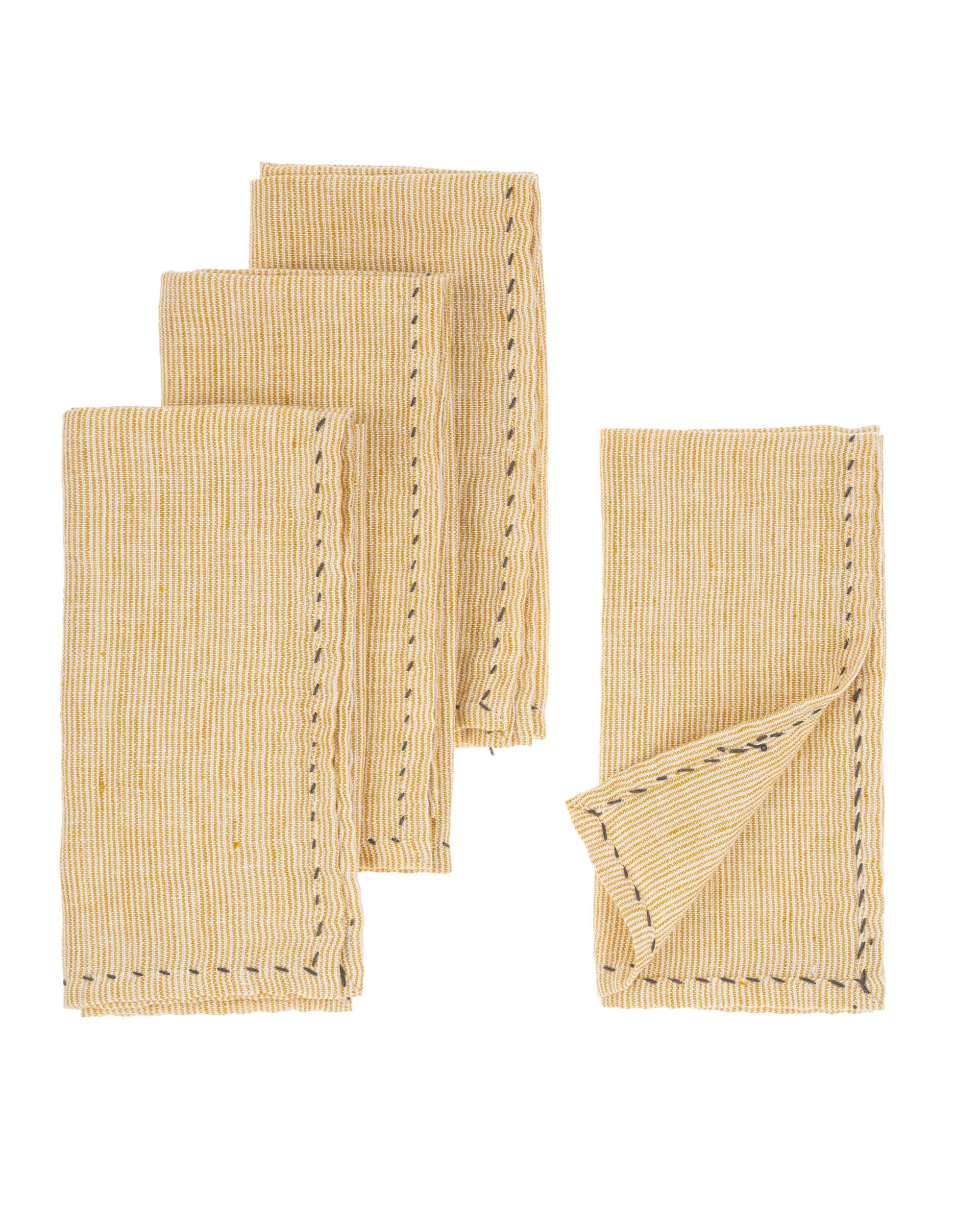 Four folded Indaba Linen Pinstripe napkins in yellow with thin white stripes and visible stitched edges, neatly arranged on a white background. One napkin's corner is slightly lifted to highlight the stitching.