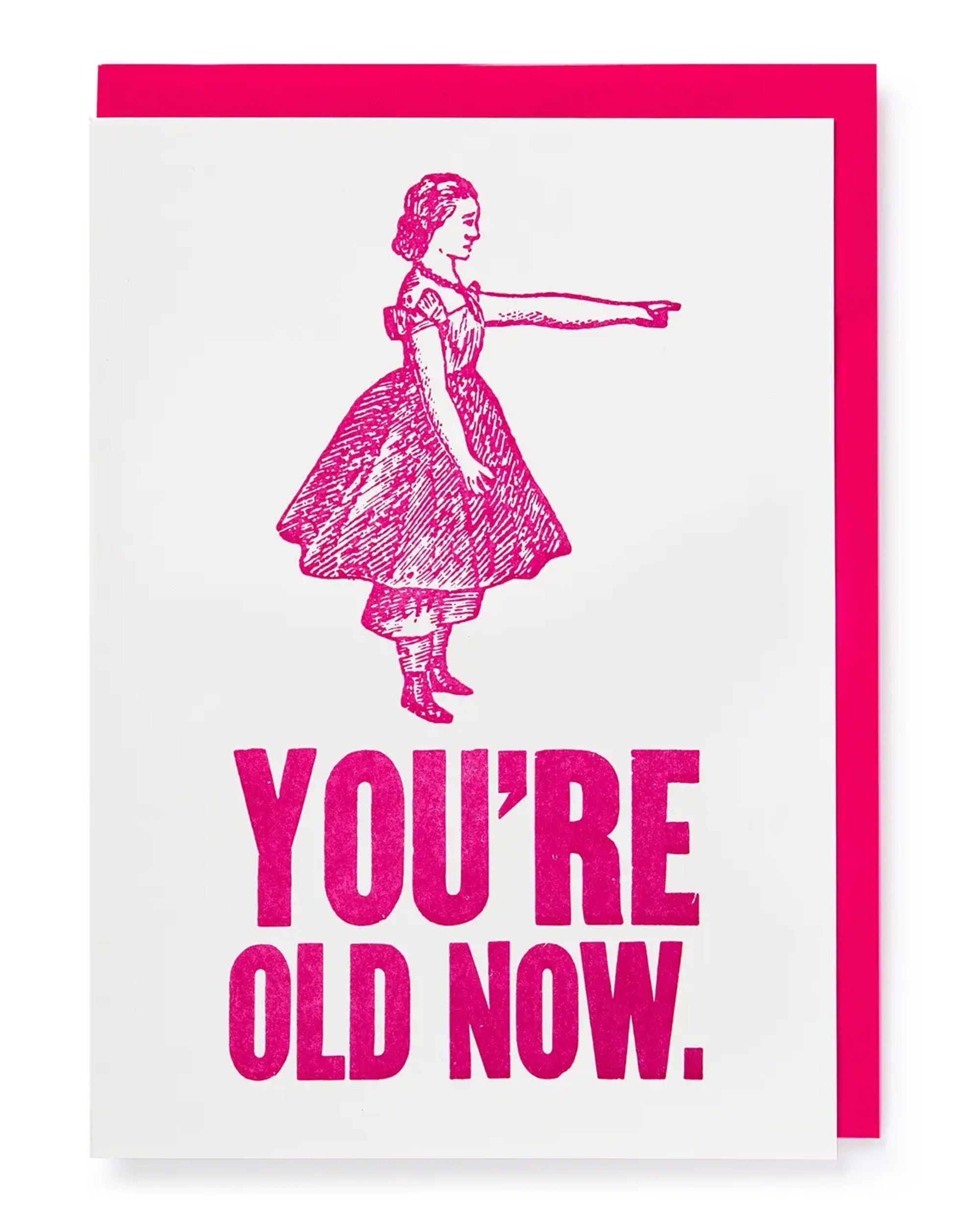 The Faire "You're Old Now Card" features a vintage-style pink illustration of a woman in a dress pointing right, bold pink text that says "YOU'RE OLD NOW," and comes with a bright envelope—perfect for birthdays.