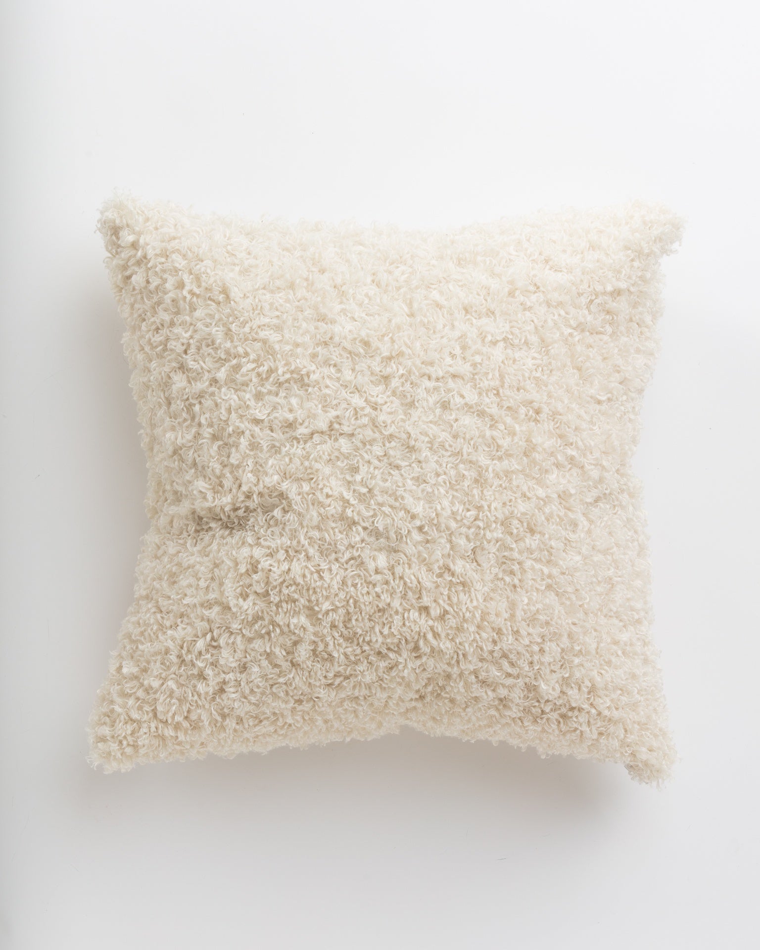 A fluffy, white textured Curly Ivory 24x24&quot; pillow isolated on a white background, providing a soft and cozy appearance, perfect for a Scottsdale Arizona bungalow from Gabby.