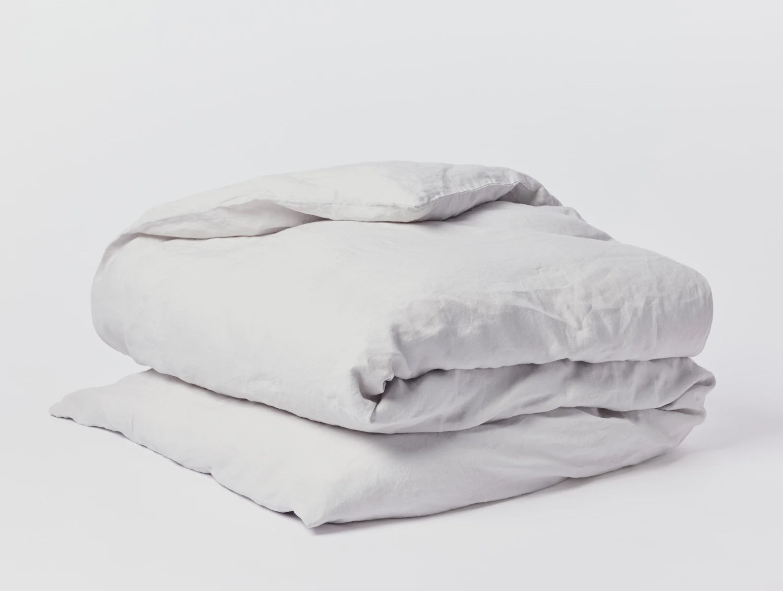 A neatly folded Coyuchi Inc Organic Relaxed Linen Duvet Cover King and pillow set against a plain white background in a Scottsdale, Arizona bungalow.