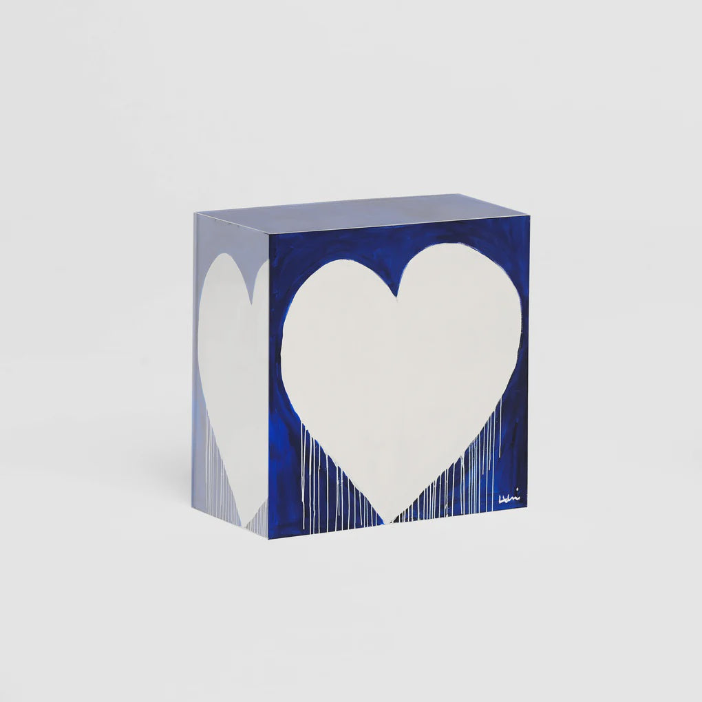 A blue cube with a large white heart on its visible sides, against a simple white bungalow-style background by Kerri Rosenthal&#39;s marvelous madness love hunk.