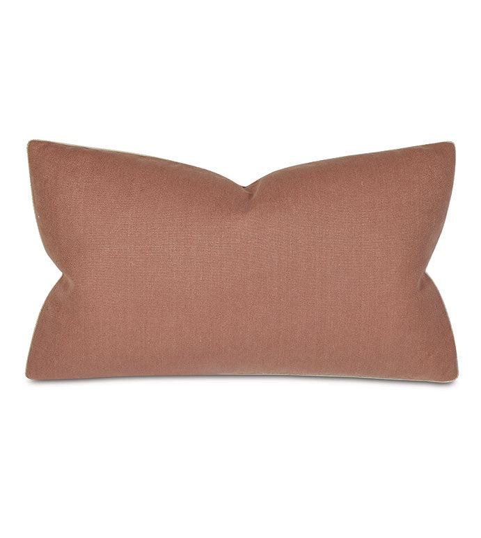 A rectangular, blush pink Ridge Linen 15x26" throw pillow from Eastern Accents with a unique bow-like pinch at the center, giving it a sculpted, two-winged shape, set against a white background in a Scottsdale Arizona bungalow.